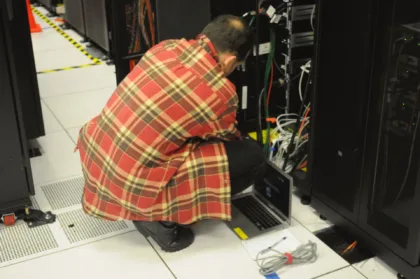 Técnico que trabaja con una computadora junto a servidores