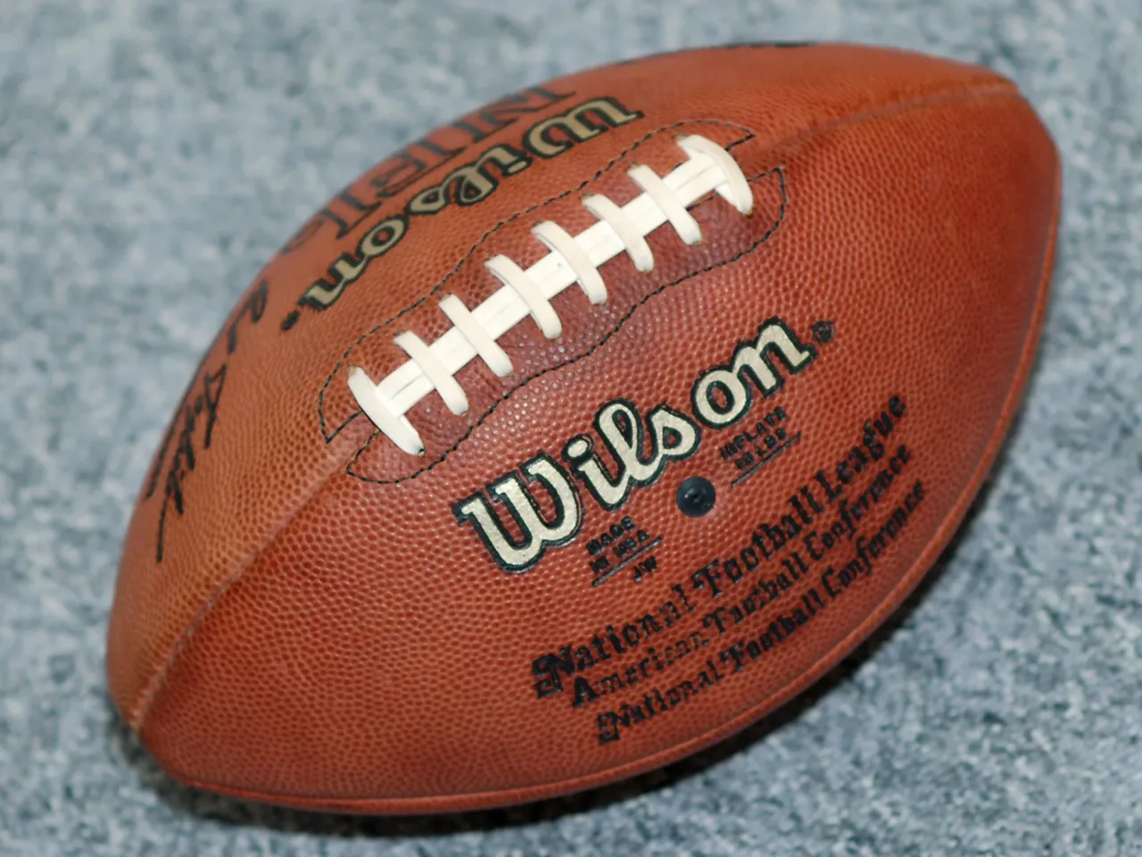 Balón marrón de fútbol americano sobre una superficie gris
