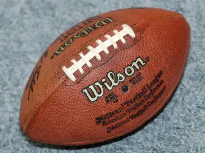 Balón marrón de fútbol americano sobre una superficie gris