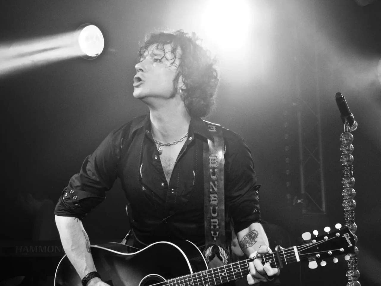 Enrique Bunbury canta y toca una guitarra en una fotografía en blanco y negro