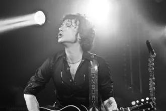 Enrique Bunbury sings and plays a guitar in a black-and-white photograph