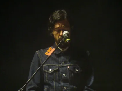 Meme del Real canta ante un micrófono sobre el escenario