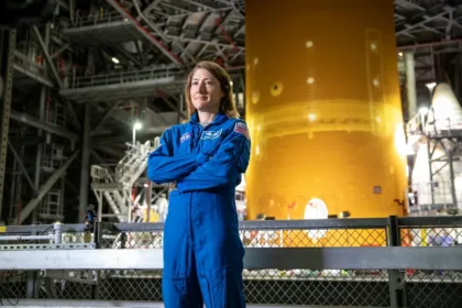 Christina Koch wearing an astronaut flight suit at a NASA facility