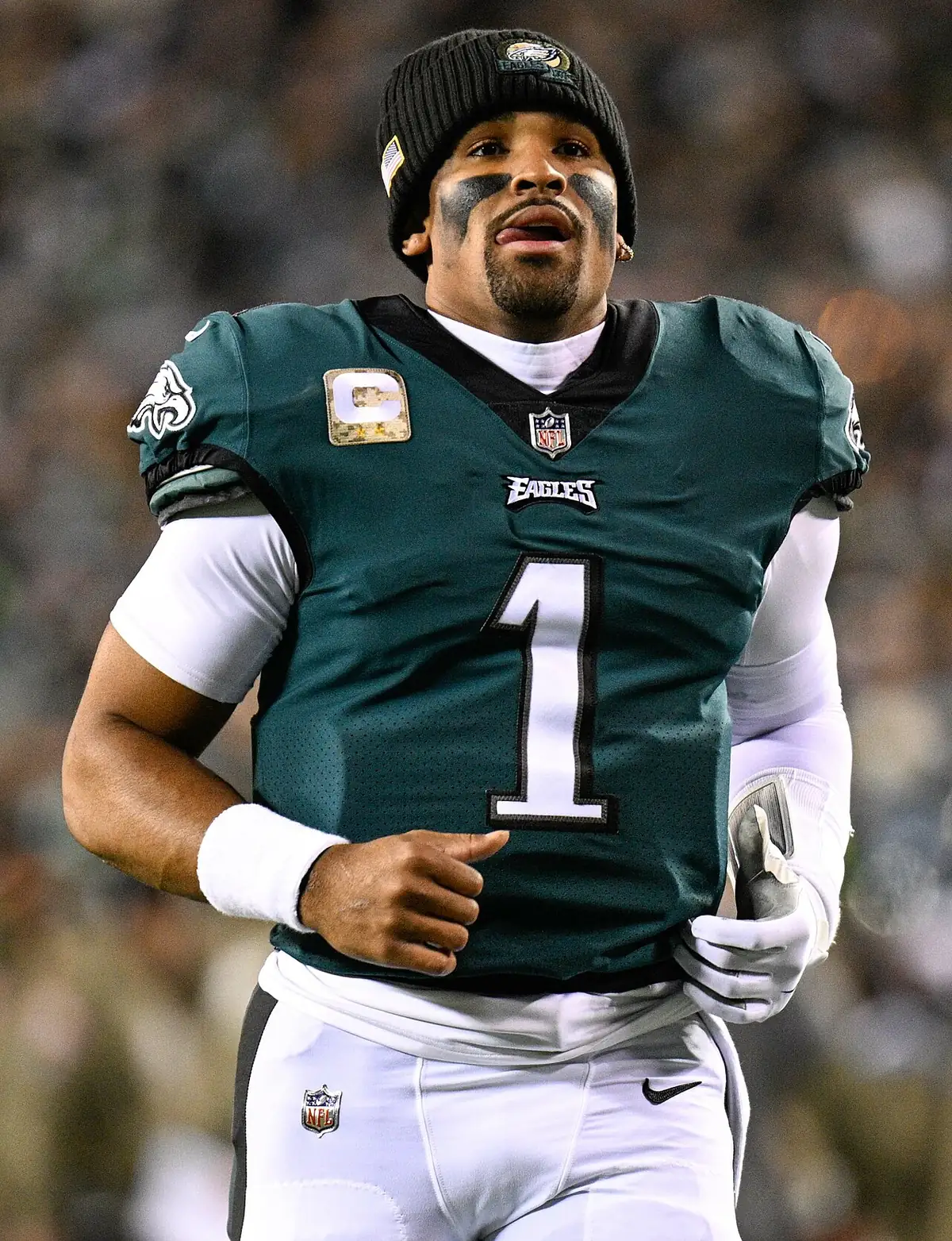 File photo from 14 November 2022: Jalen Hurts, wearing a Philadelphia Eagles uniform and a black beanie, appears in the foreground with a blurred stadium in the background.