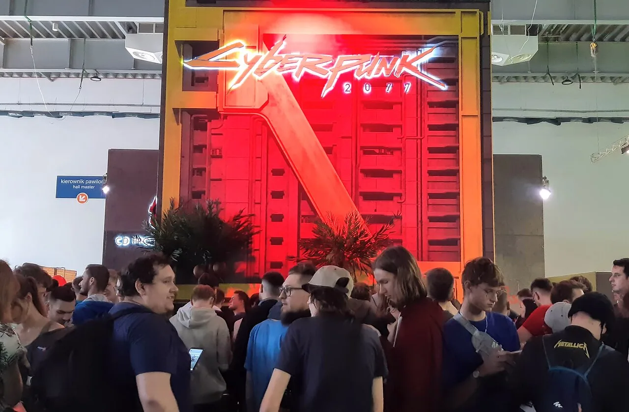 File photo of the Cyberpunk 2077 booth at Poznań Game Arena, with the game's large sign and attendees in the foreground, taken on October 20, 2019.