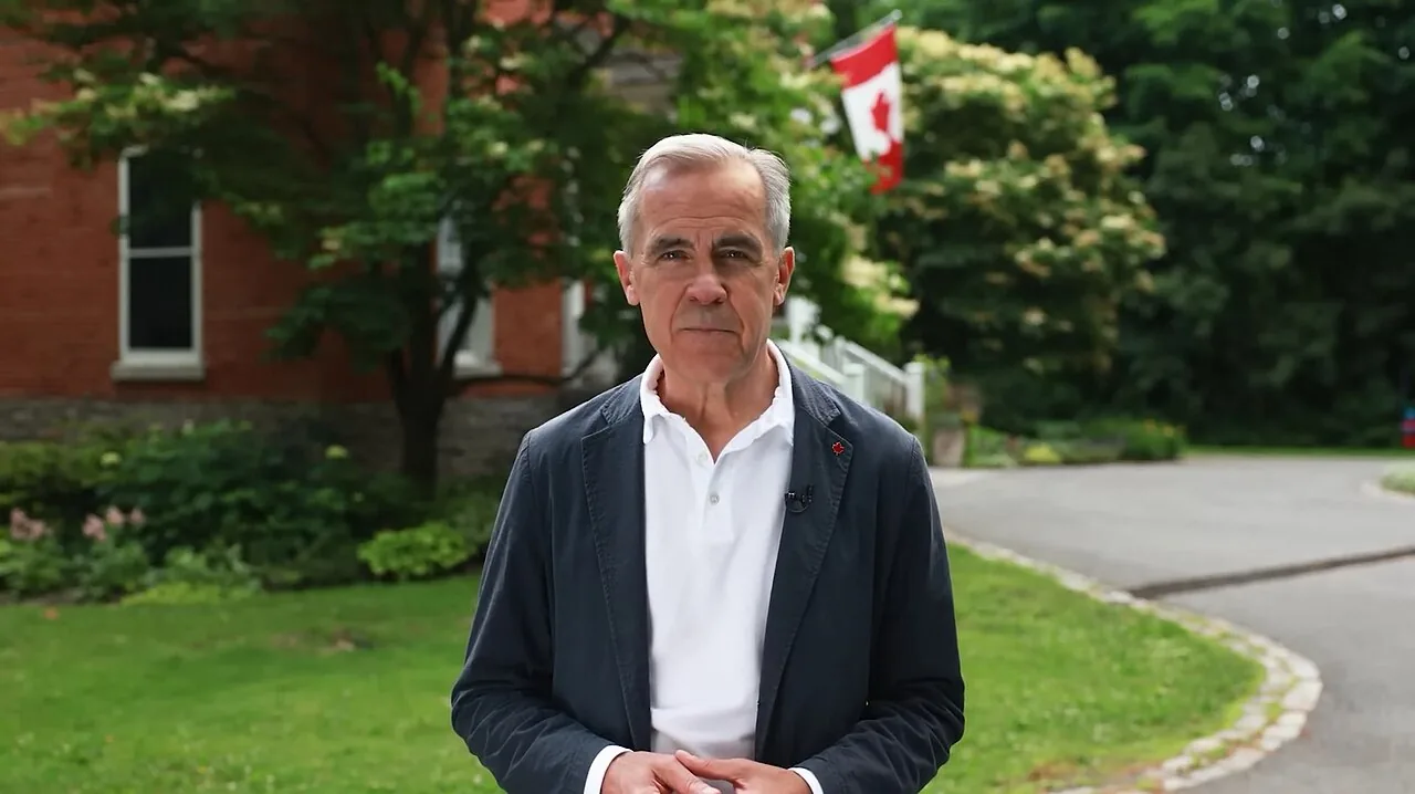 File photo from July 1, 2025: Mark Carney, standing outdoors in front of greenery and a Canadian flag, looking at the camera.