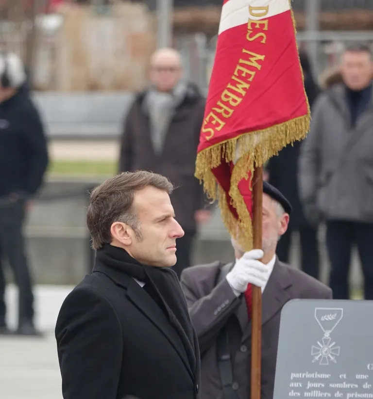 File photo from February 2, 2025: Emmanuel Macron, wearing a black coat and scarf, during the ceremony marking the 80th anniversary of the liberation of Colmar; a red banner appears beside him, co