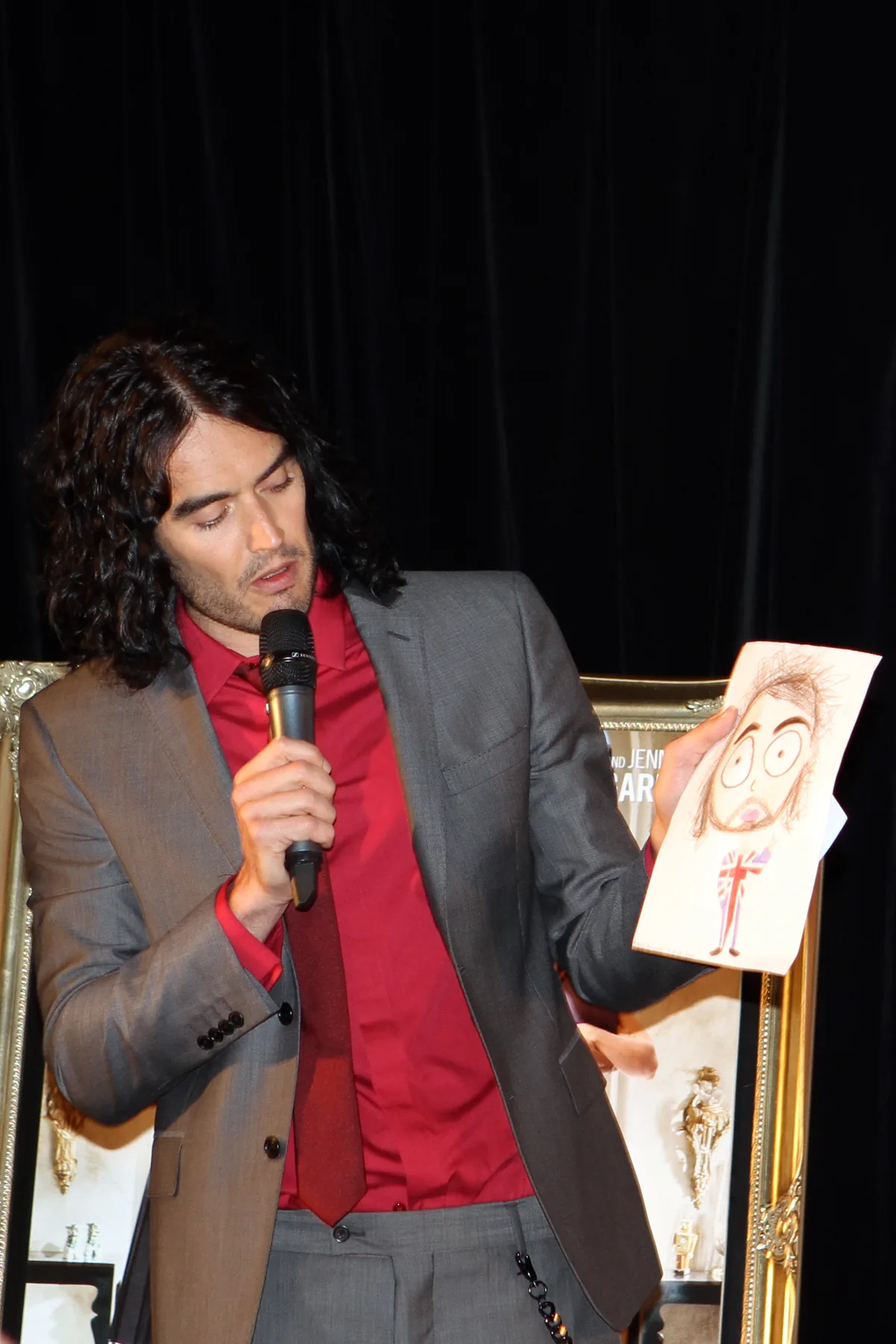 Foto de archivo de Russell Brand, con un micrófono y sosteniendo una ilustración, el 15 de abril de 2011.