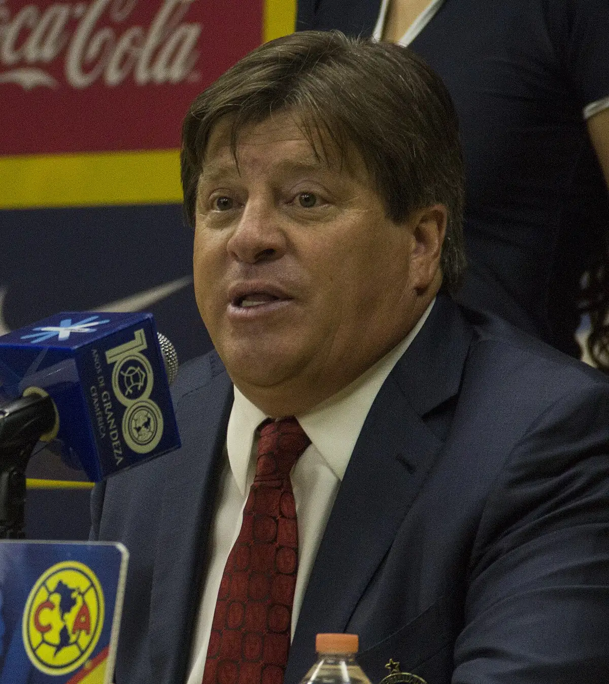 File photo from 9 of April 2016: Miguel Herrera, wearing a suit and tie, appears alongside microphones bearing Club América emblems.